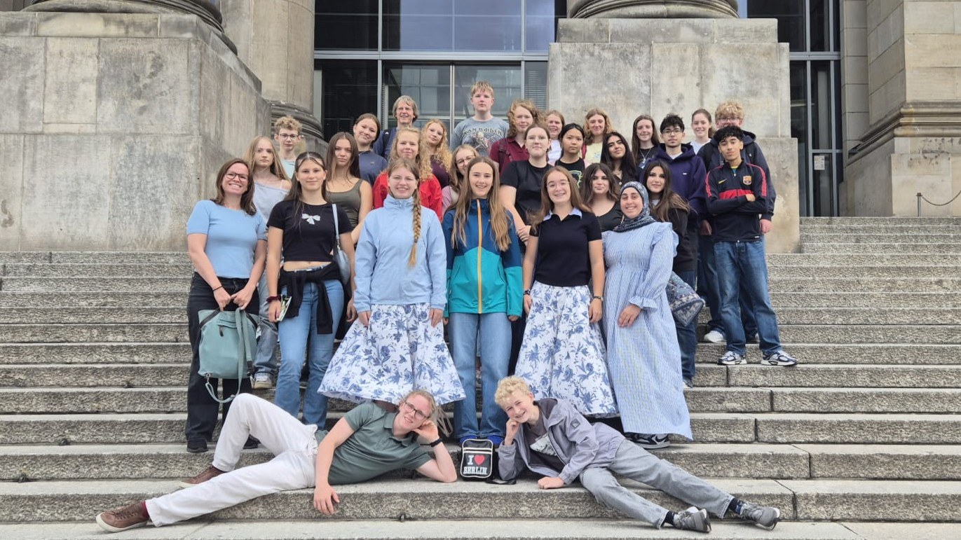 Eine zehnte Klasse auf einer breiten Steintreppe vor einem Gebäude in Berlin