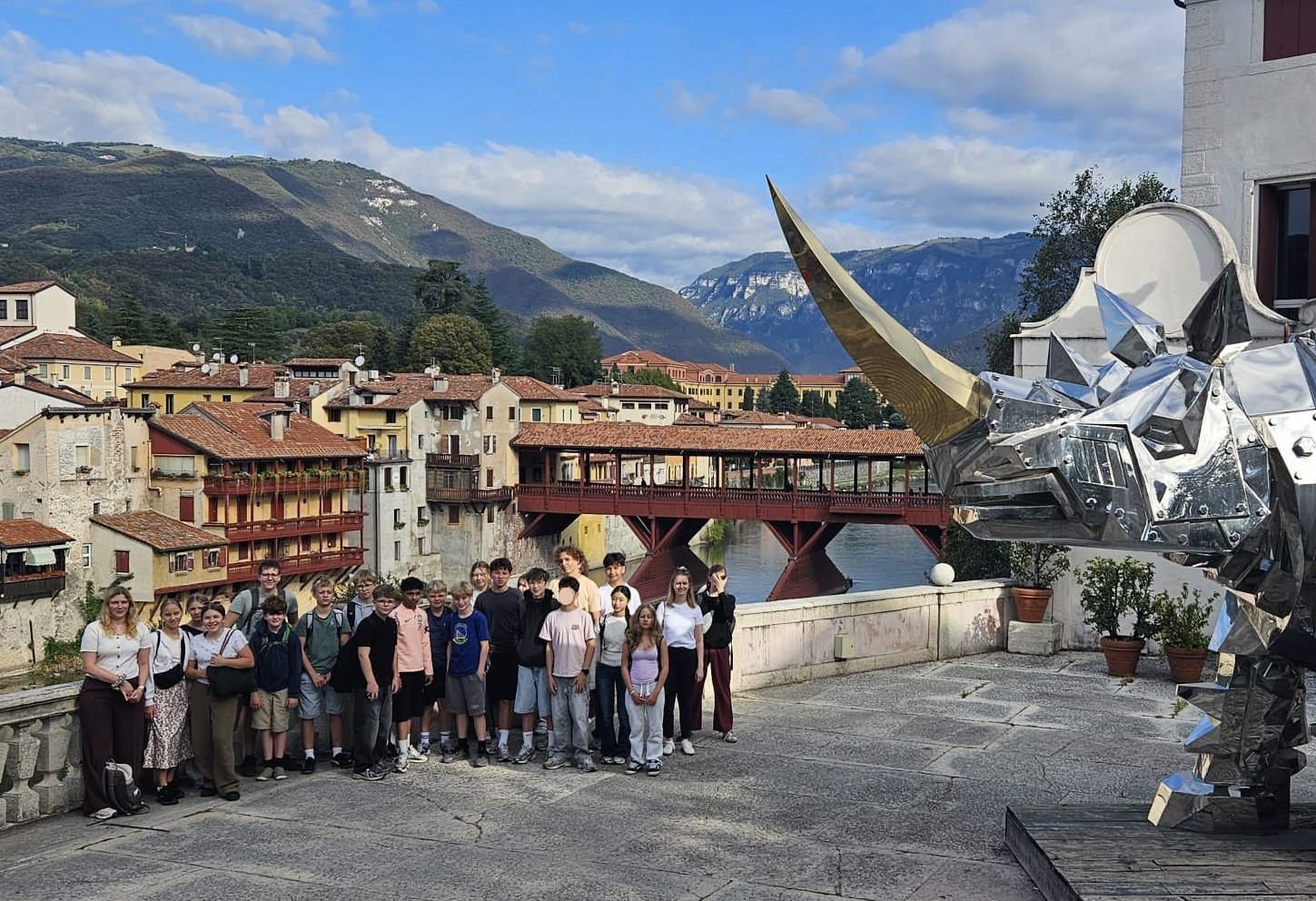 Die Klasse 8mu auf einer Terrasse in Bassano del Grappa, im Hintergrund die überdachte Holzbrücke über die Brenta und die Berge